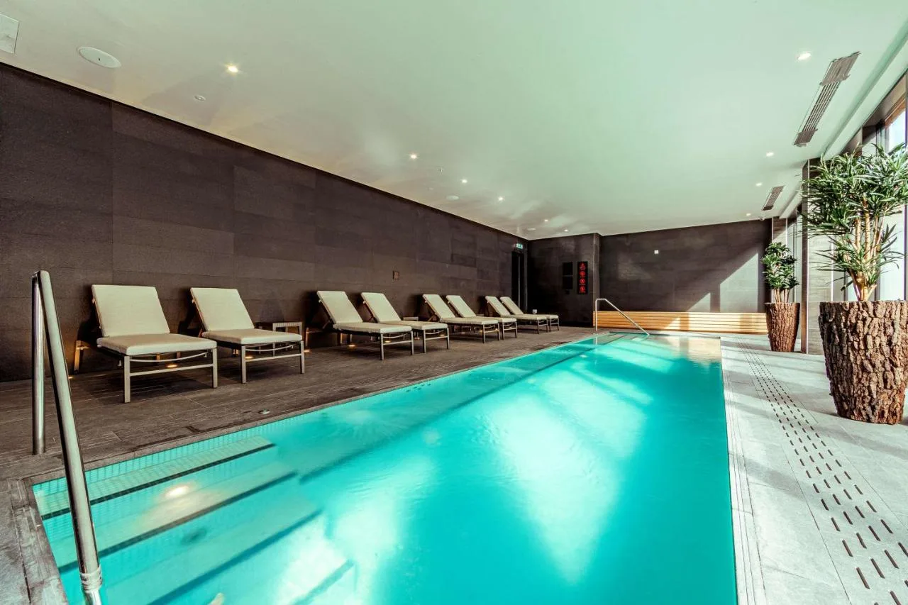 a swimming pool in a hotel room with chairs at The Fellows House Cambridge, Curio Collection By Hilton in Cambridge